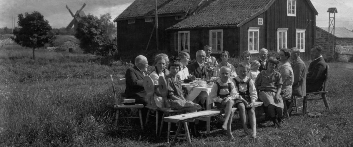 Människor vid ett bord frakför att hus och en väderkvarn i bakgrunden