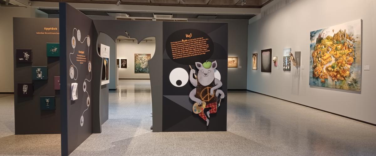 visar en vy över basutställningen med en bild på konstmuseets maskot Busis och olika konstverk i bakgrunden