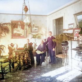 Ett färglagt foto av en interiör från sent 1800-tal med te personer i mitten