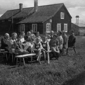 Människor vid ett bord frakför att hus och en väderkvarn i bakgrunden