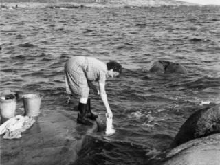 Elin Karlsson sköljer tvätt (Foto: Ålands landskapsarkiv)