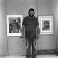 Konstnären Guy Frisk står framför ett par tavlor