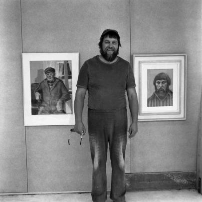 Konstnären Guy Frisk står framför ett par tavlor