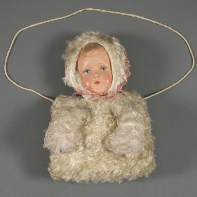 beige muff med insytt dockhuvud, framsida